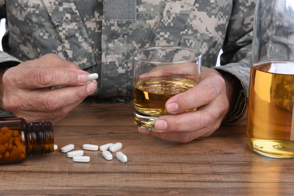 A soldier with whiskey and pills showing the the link between addiction and PTSD.